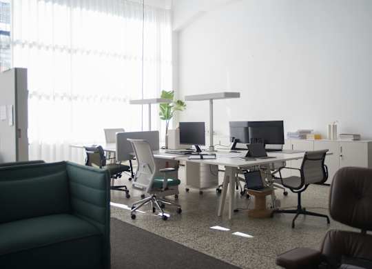 A modern office with a green chair and a desk with a laptop and a plant on it.
