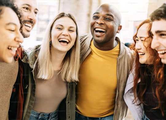 A group of people are standing close together and laughing.