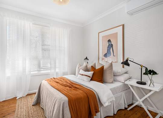 A bedroom with a bed, a nightstand, and a painting on the wall.