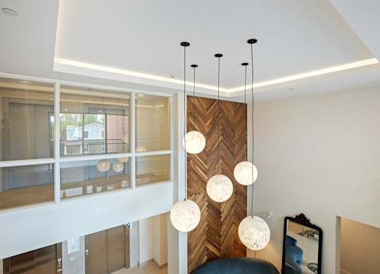 A modern interior with a wooden panel and hanging lights.