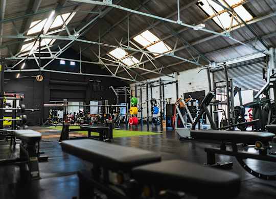 A gym with a variety of equipment including weight benches and a squat rack.