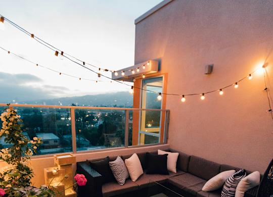 a patio with couches and lights on a balcony