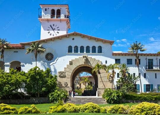a white building with a clock tower and palm trees