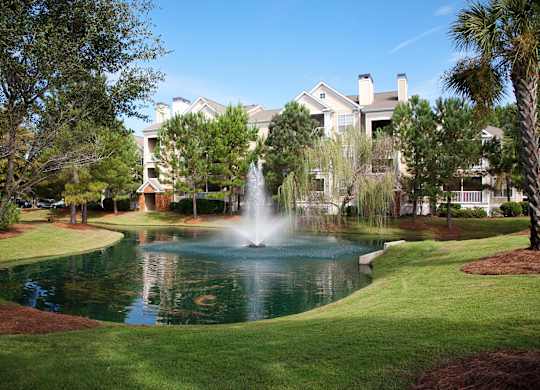 a fountain in the middle of a pond in front of a building