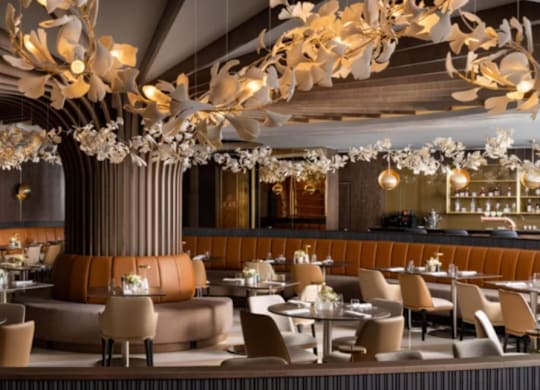 A modern restaurant with a central column and chandeliers.