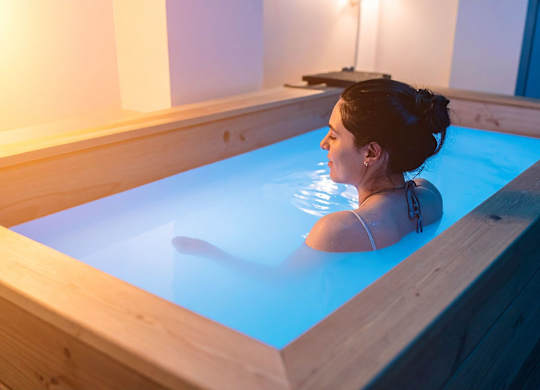 A woman is sitting in a blue hot tub.