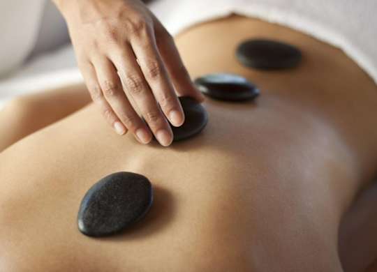 A person receiving a hot stone massage on their back.