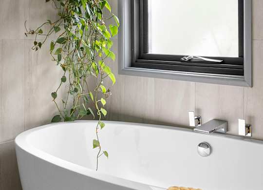 A white bathtub with a silver faucet and a mirror above it.