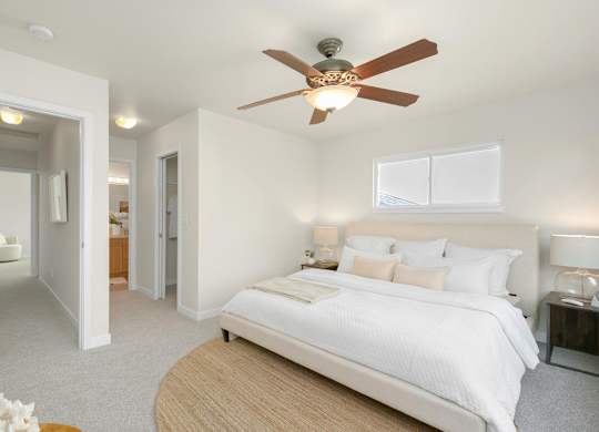 A bedroom with a large bed and a ceiling fan.