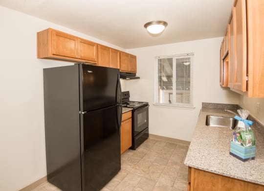 Todd Village vacant apartment kitchen with black appliances and wood cabinets