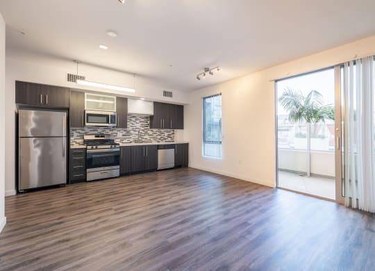 an empty living room with a kitchen and sliding glass doors