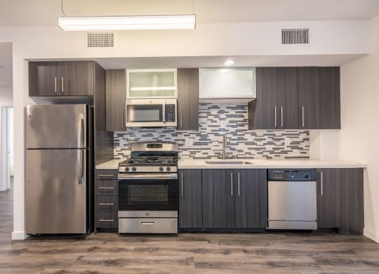 a modern kitchen with stainless steel appliances and dark wood cabinets