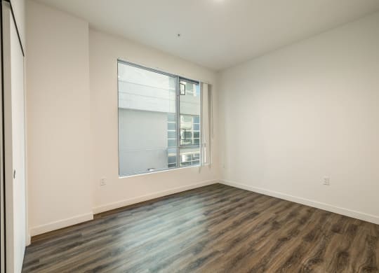 an empty living room with a large window and wood flooring