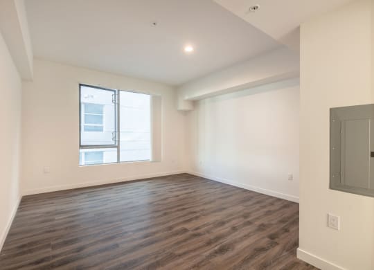 an empty living room with wood flooring and a window