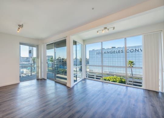 a living room with wood flooring and large windows and a balcony