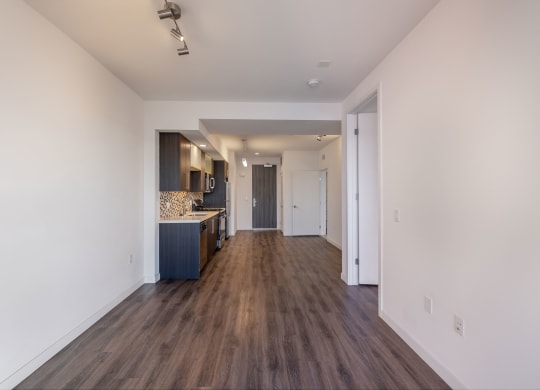 a living room and kitchen with white walls and wood flooring
