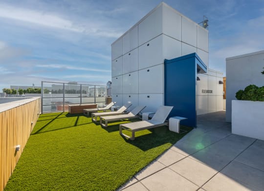 a rooftop terrace with lounge chairs and a building in the background