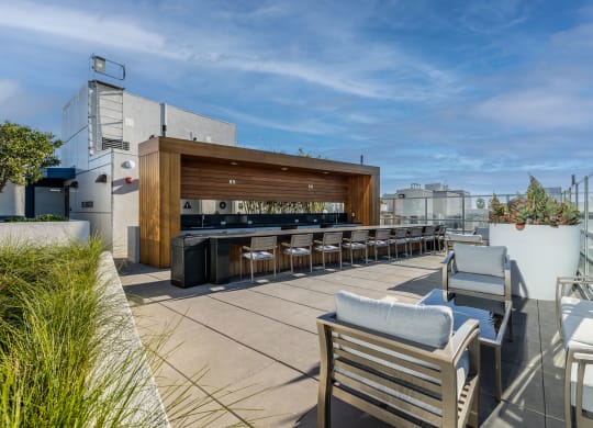 a rooftop patio with a bar and chairs and furniture