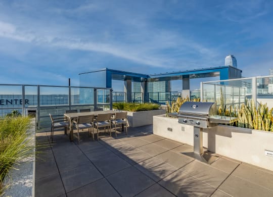 a patio with a barbecue grill and tables on a roof