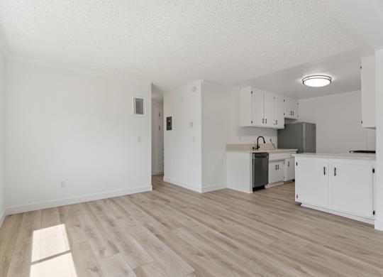 A kitchen with white cabinets and a wooden floor.