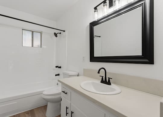 A white bathroom with a toilet, sink, and mirror.