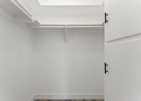 A white closet with a white door and a white shelf above it.