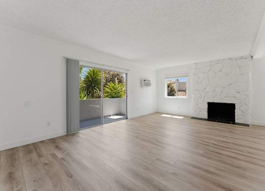 A room with a fireplace and a sliding glass door leading to a balcony.