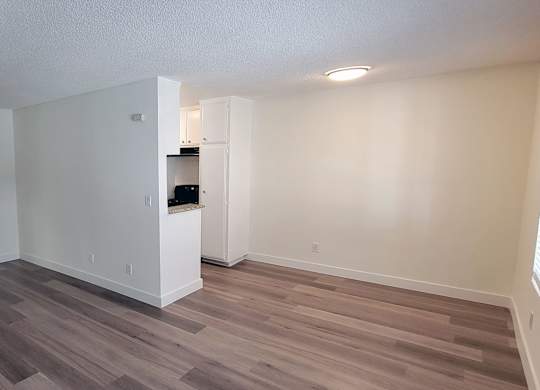 A room with wooden flooring and white walls.