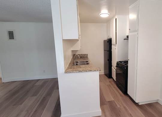 A kitchen with a white island and a black refrigerator.