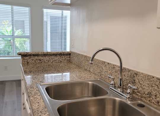 A kitchen with a granite countertop and a stainless steel sink.