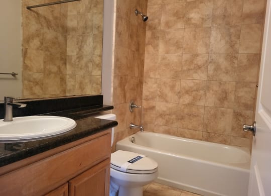 Elegant tile bathroom with white fixtures and granite counter top at The Cove at Bear Valley in Escondido, California.