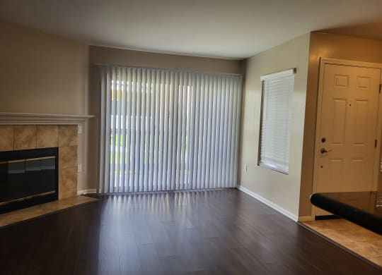 Living room with plank style flooring, beautiful fireplace and lots of windows at The Cove at Bear Valley in Escondido, California.
