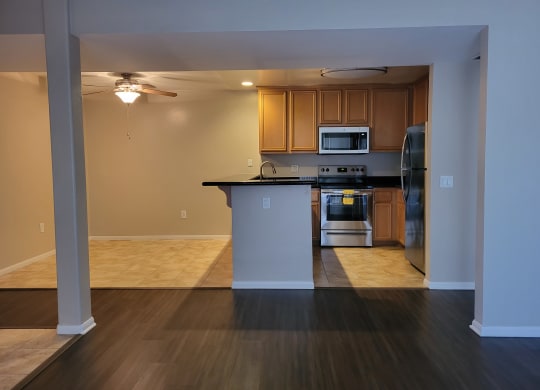 Living room view of kitchen and dining room with ceiling fan and tile floors at The Cove at Bear Valley in Escondido, California.