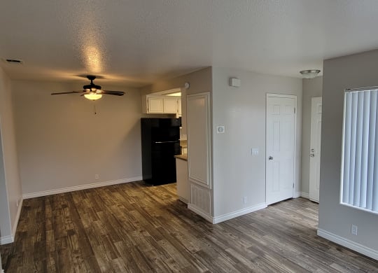 Living room view of enterance, front closet, dining area with ceiling fan and kitchen at Lakeshore Terrace Apartments in Lakeside, California.