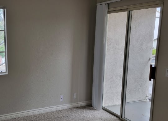 Carpeted bedroom with sliding door access to porch at Lakeshore Terrace Apartments in Lakeside, California.