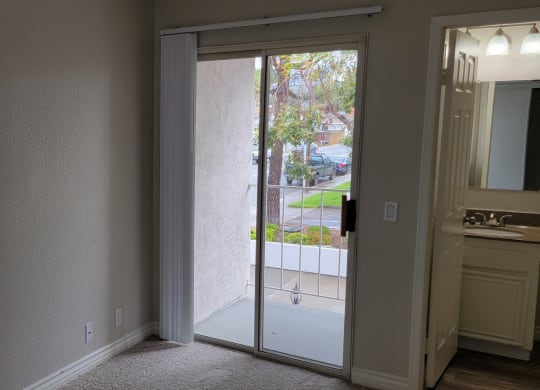 Porch access from carpeted bedroom with lots of natural light at Lakeshore Terrace Apartments in Lakeside, California.