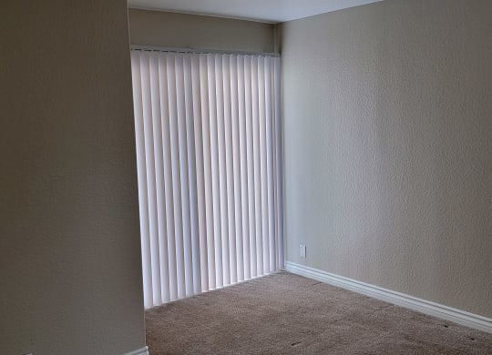 Carpeted bedroom with sliding glass door to porch at Lakeshore Terrace Apartments in Lakeside, California.