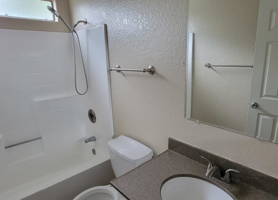 Bathroom with white fixtures and natural light at Lakeshore Terrace Apartments in Lakeside, California.