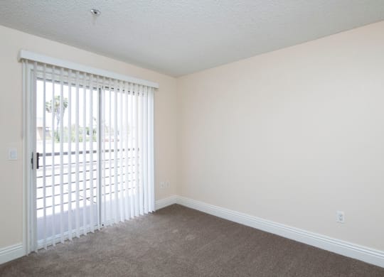 Carpeted bedroom with balcony at the Atrium Apartments in San Diego, California.