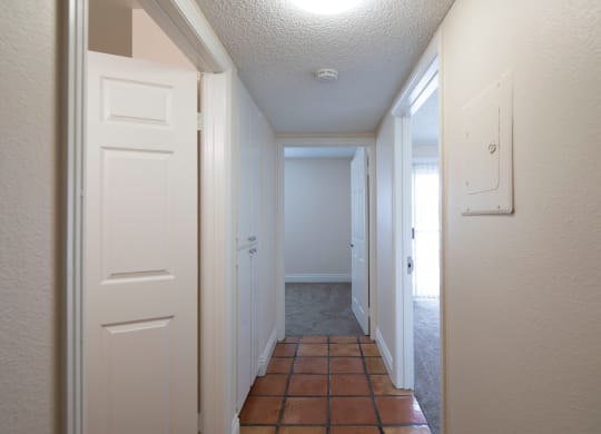 Bedroom hallway with Saltillo tile flooring and closet space at the Atrium Apartments in San Diego, California.