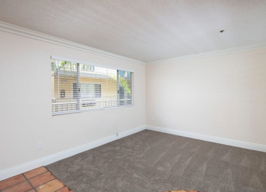 Front room with custom blinds over large window at the Atrium Apartments in San Diego, California.