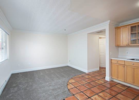 Open kitchen with Saltillo tile flooring and front room with berber carpeting and large window at the Atrium Apartments in San Diego, California.