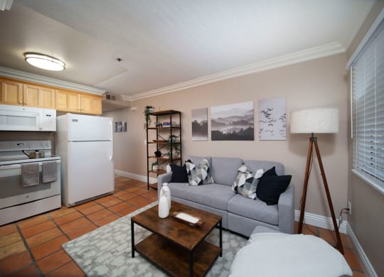 Living room with large window and open kitchen in model unit at the Atrium Apartments in San Diego, California.
