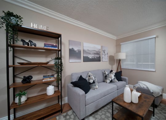 Living room in model unit with Saltillo tile floors, crown molding, and custom window binds at the Atrium Apartments in San Diego, California.