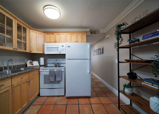 Model unit kitchen with spacious wooden cabinets, granite countertops, and electric appliances at the Atrium Apartments in San Diego, California.