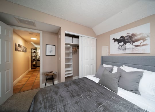 Bedroom in model unit showing spacious closets and berber carpet at the Atrium Apartments in San Diego, California.