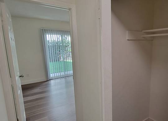 A white door is open to a room with a window and a balcony.