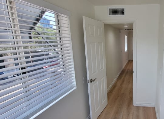 Bedroom with mirrored closet doors and lots of natural light in one bedroom apartment at the Atrium Apartments in San Diego, CA.