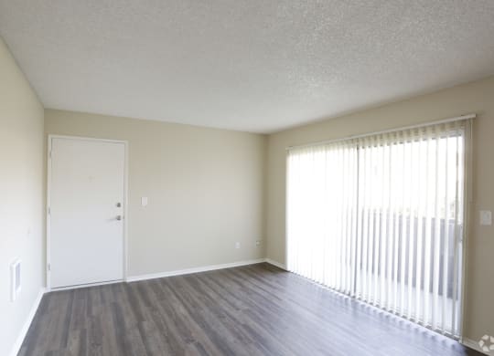 Living room with front door and sliding glass doors to private porch at Villa Pacific Apartments in Oceanside, California.