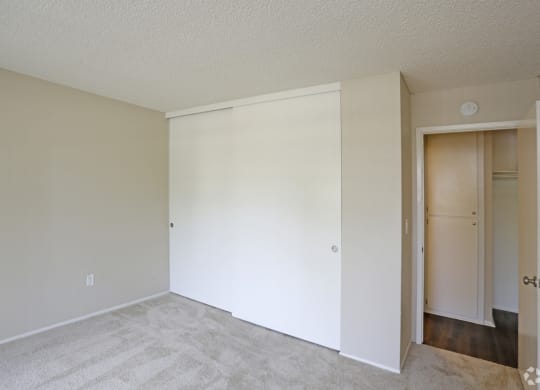 Carpeted bedroom with large closet at Villa Pacific Apartments in Oceanside, California.